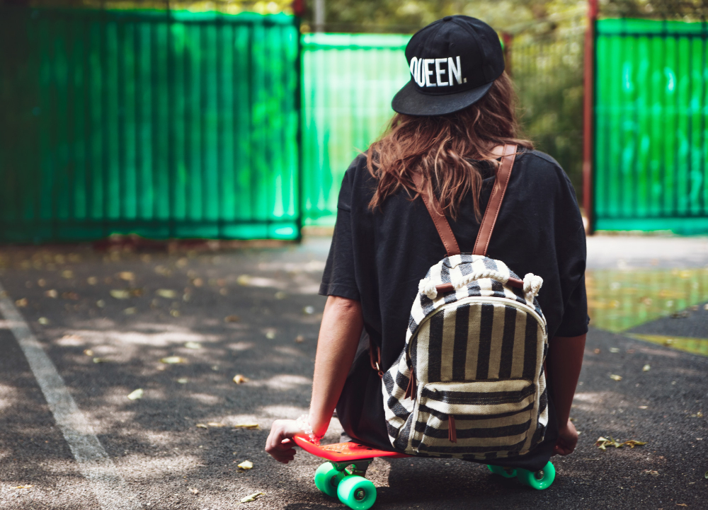 Garota sentada em skate com estampas de bonés